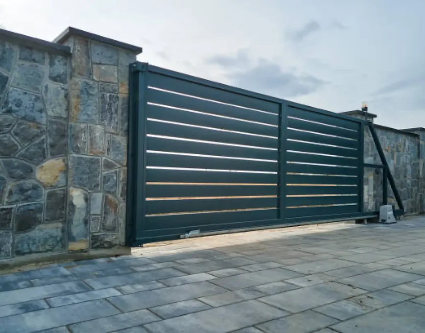 Dark grey slatted sliding gate between natural stone walls