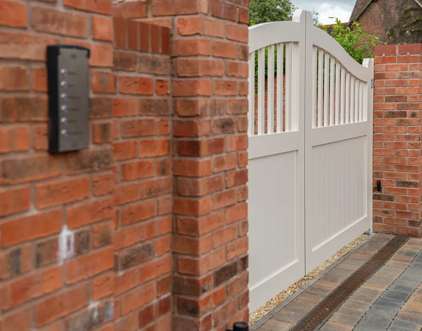 Keypad entry on a brick pier beside cream automated swing gates, near Bromsgrove