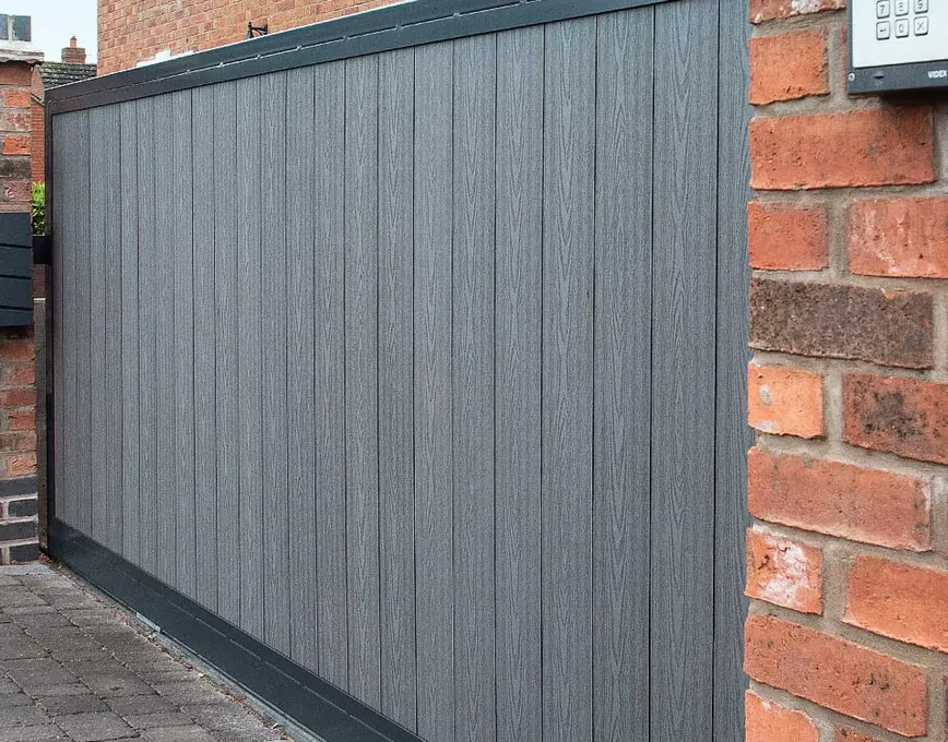 Keypad entry beside a grey composite driveway gate