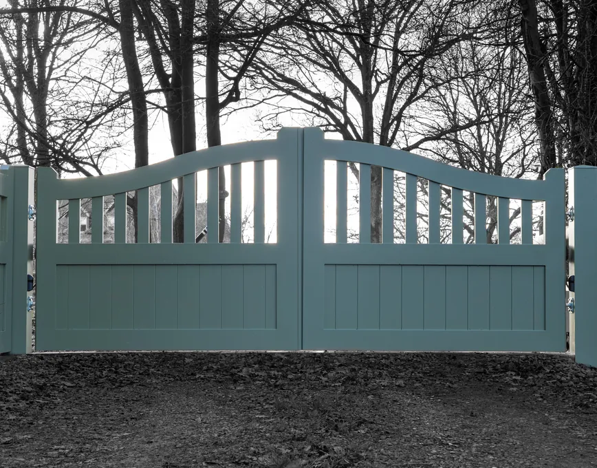 Sage green swing driveway gates with a curved spindle top
