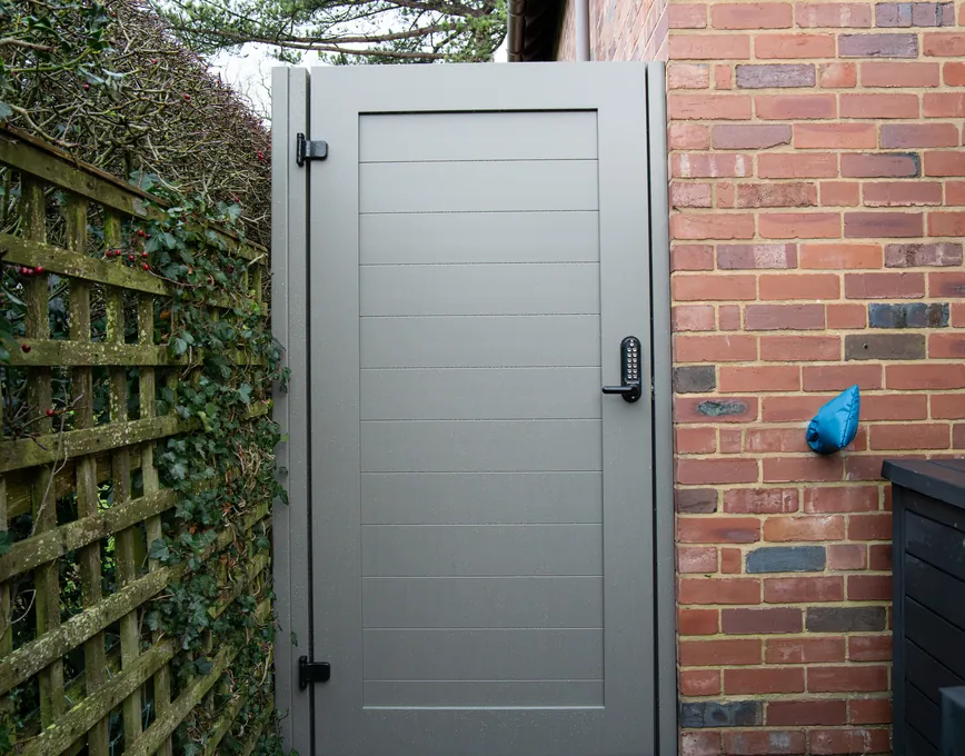 Solid warm grey privacy gate at the side of a house