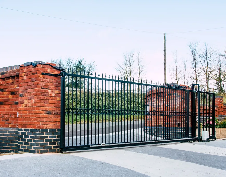 Black railed steel sliding gate across a driveway