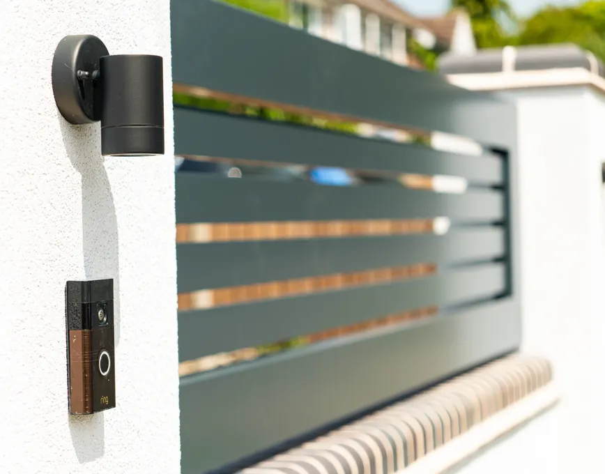 Video doorbell and wall light on a rendered pier beside a sliding gate, Cookhill
