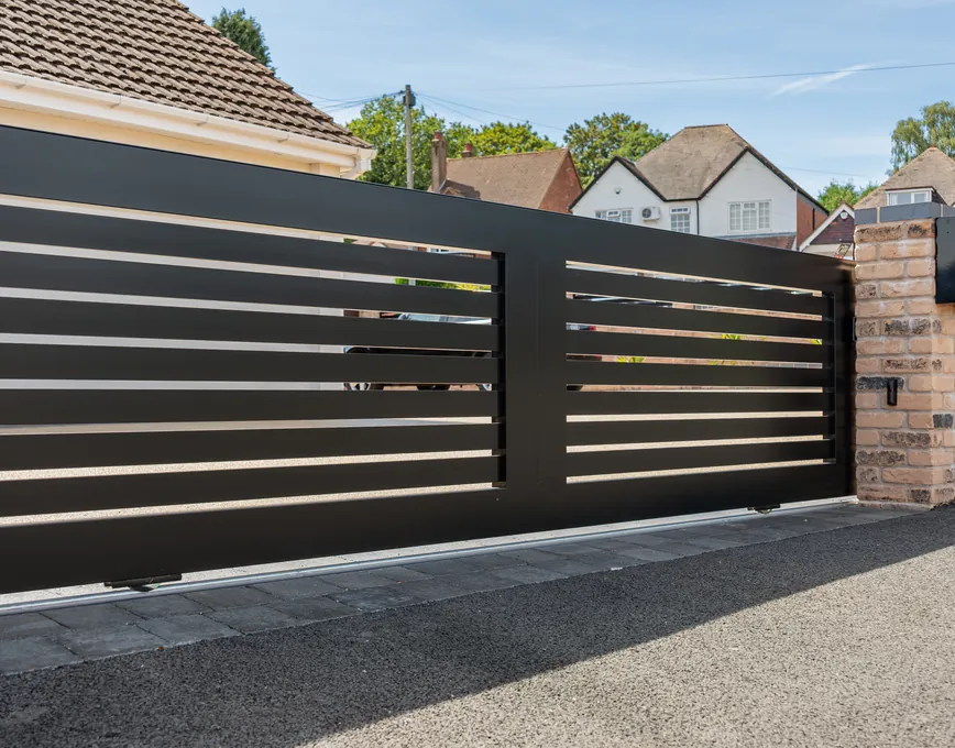 Black horizontal-slat sliding gate between brick piers, Sutton Coldfield
