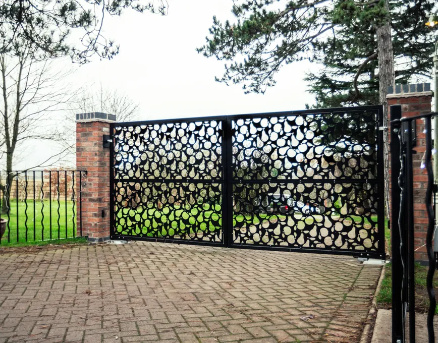 Black laser-cut steel swing gates between brick piers