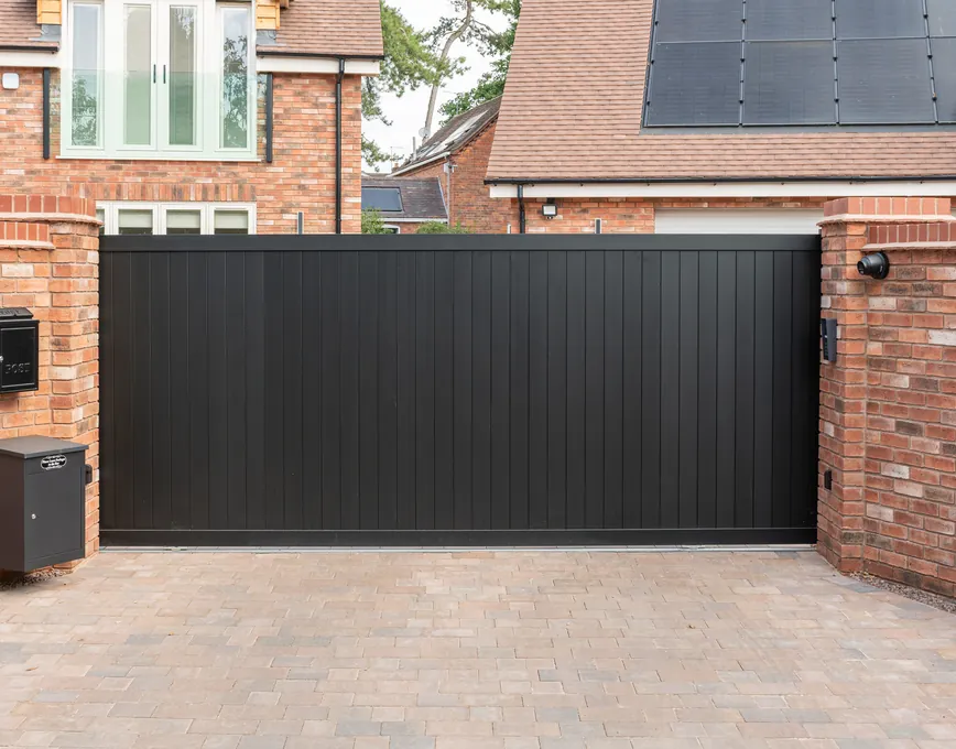 Solid black vertical-board privacy gate between brick piers