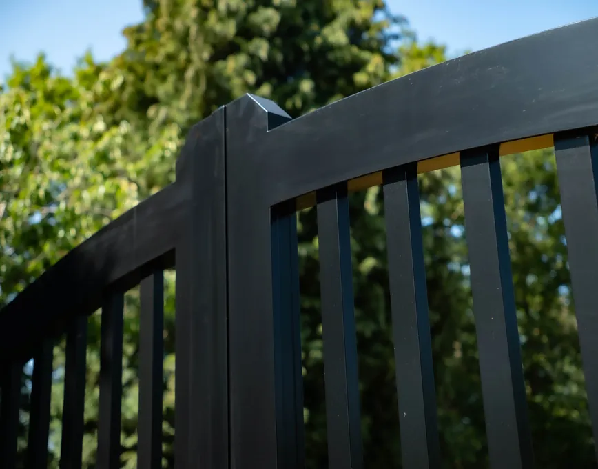 Curved top rail detail of a black swing gate