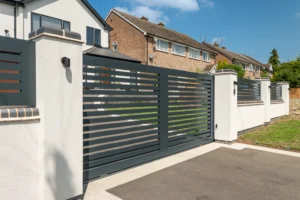 Modern anthracite grey aluminium driveway gates with horizontal slat panels and white piers, installed by Capitan Gates at Caldwell Hill, Cookhill, Worcestershire.
