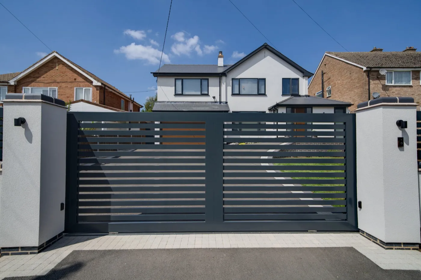 Aluminium slat sliding gate between rendered pillars, near Redditch