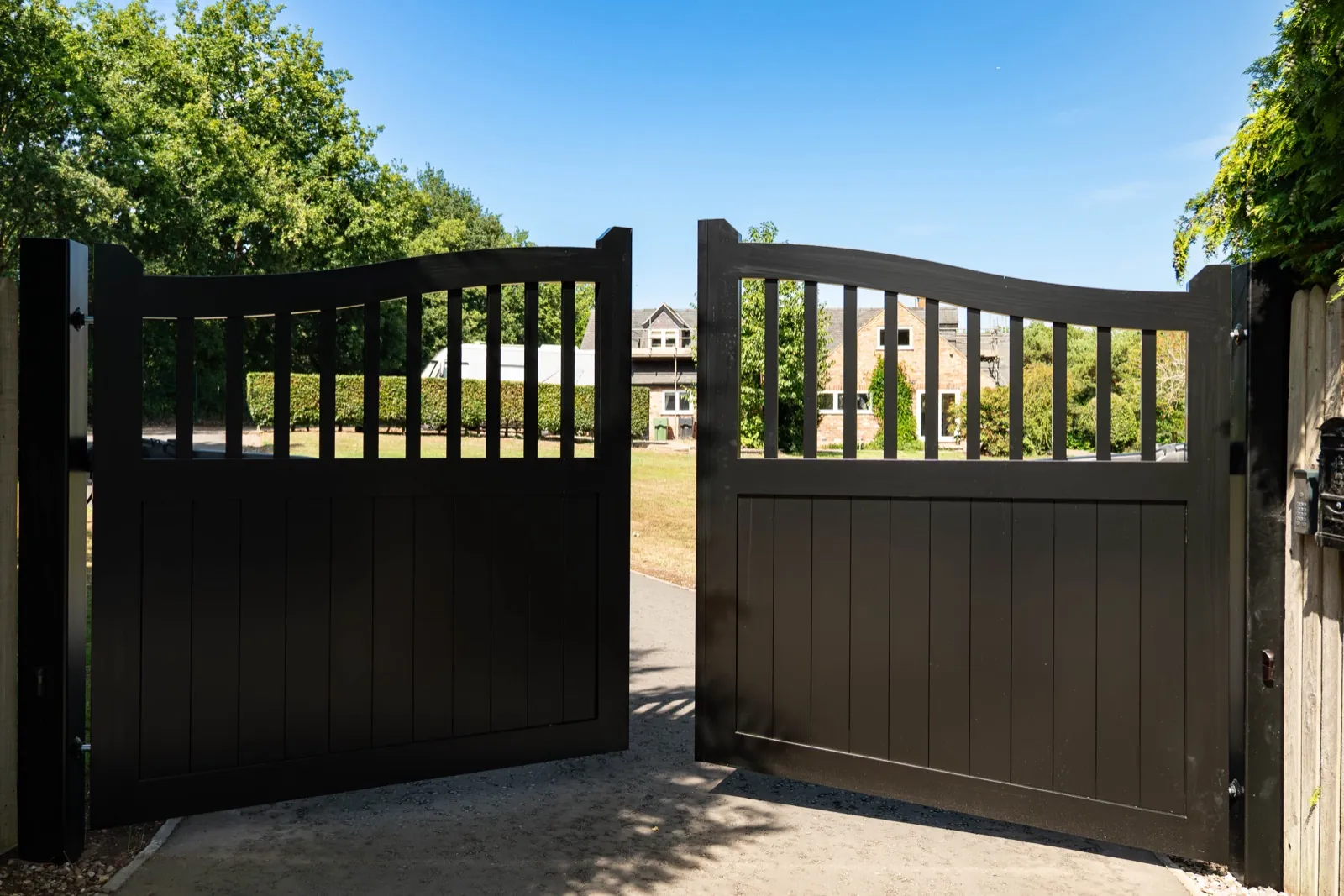 Black swing gates standing open onto a long drive