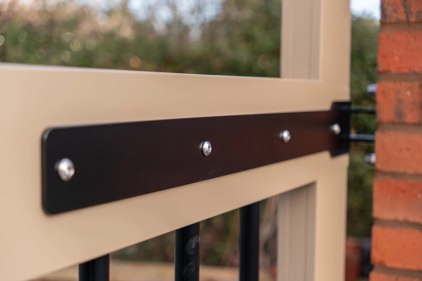 Black strap hinge on a stone-coloured gate