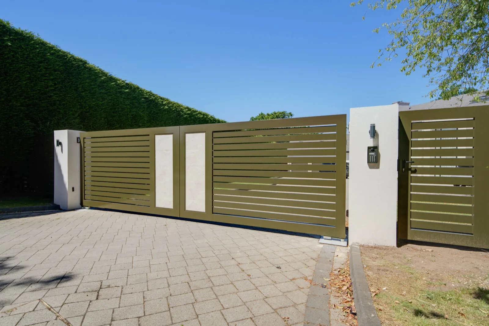 Olive green driveway gates and matching pedestrian gate beside a white rendered pier with keypad