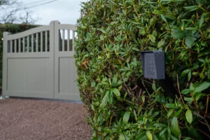 Warm grey traditional driveway gates with a keypad on a post beside the hedge, Rowington