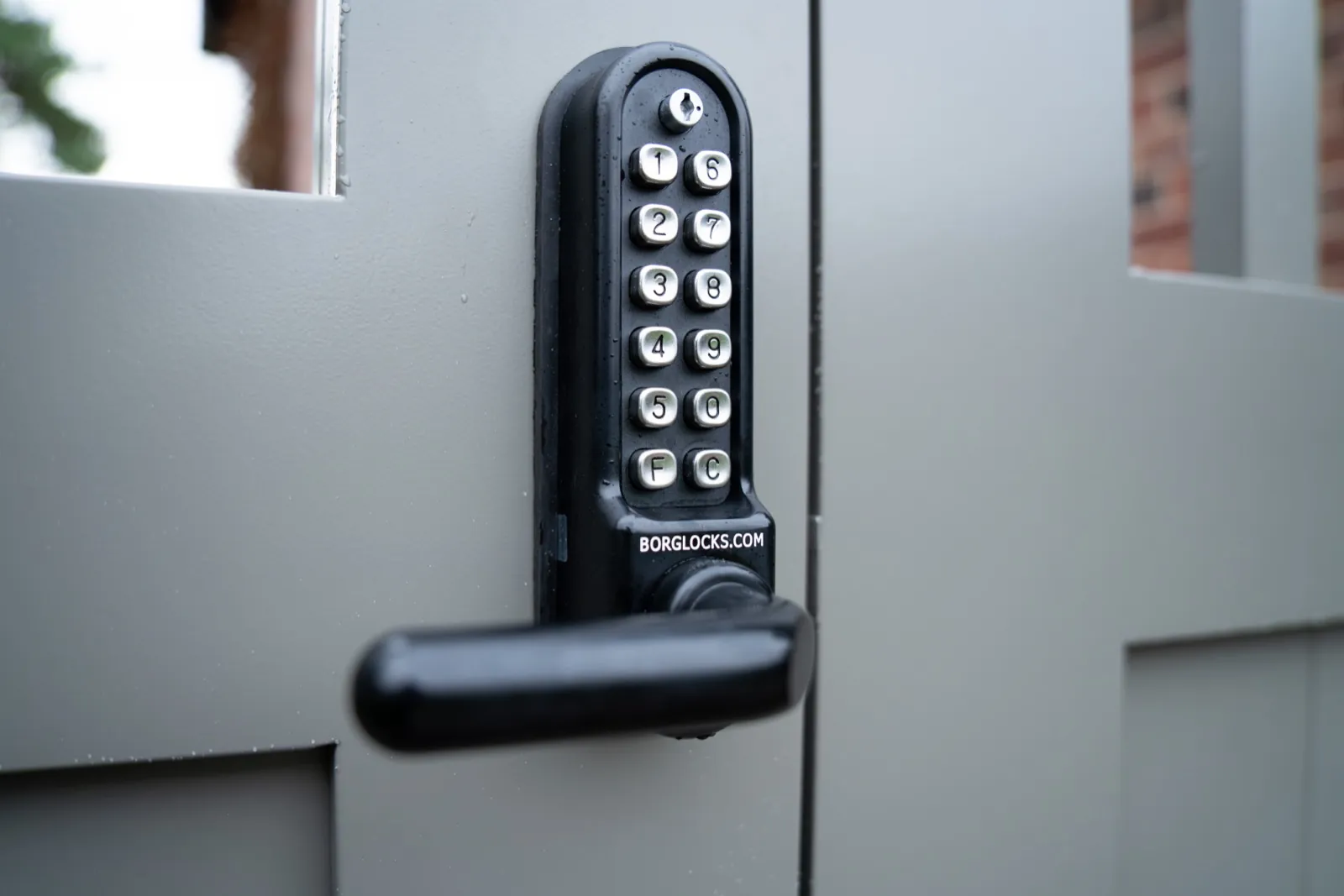 Coded lock and handle on a warm grey side gate