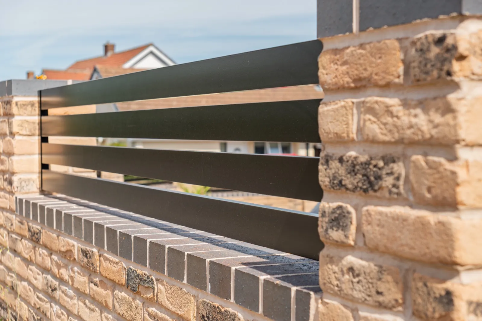 Matching black railing panel set between brick piers on the boundary wall