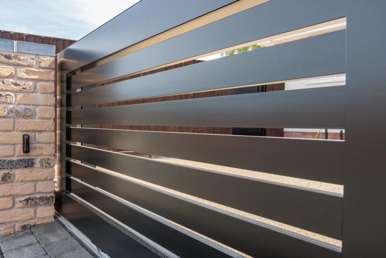 Close-up of the black sliding gate's horizontal slats