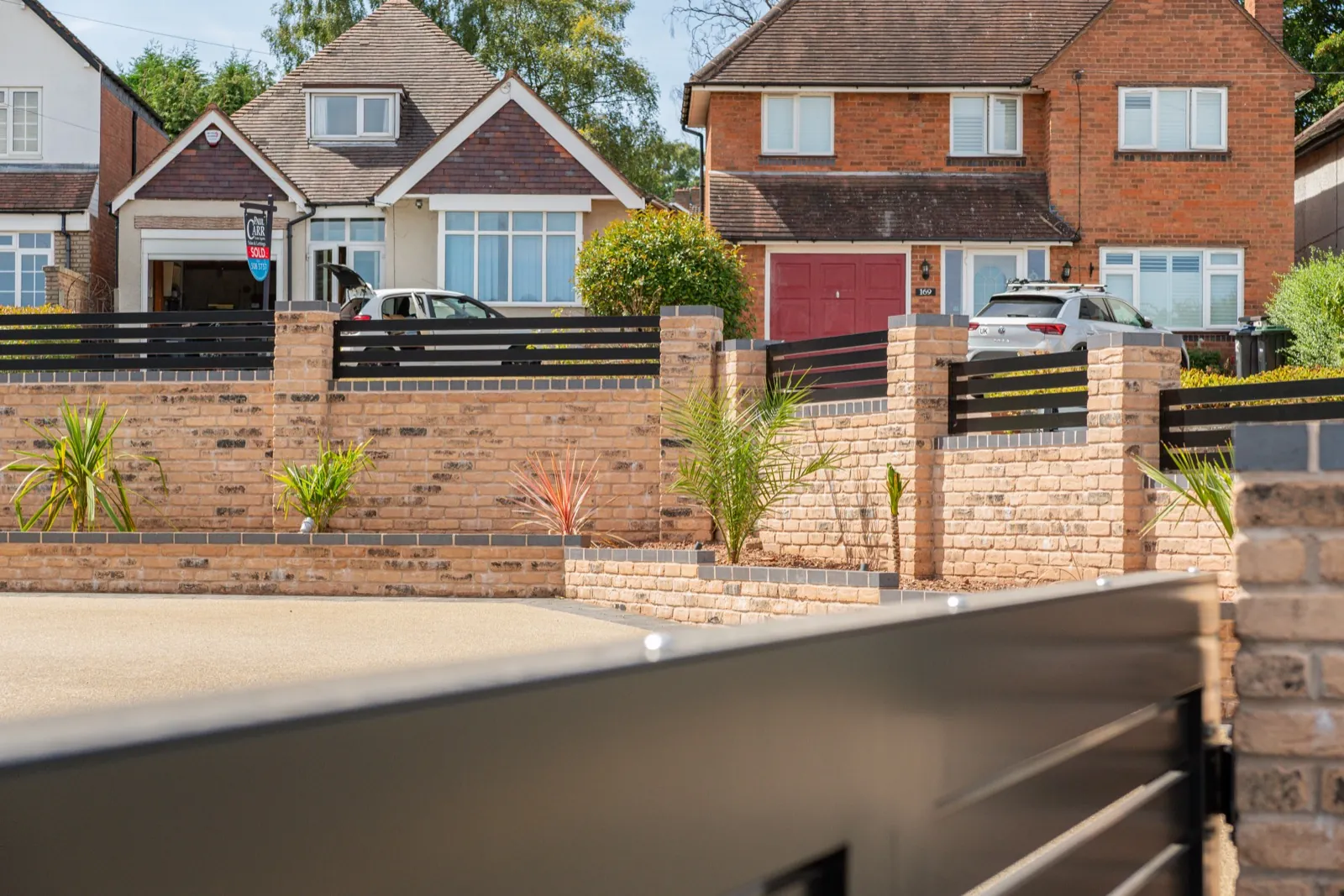 View across the finished boundary with black railings and planting