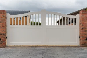 Pair of cream swing driveway gates with a curved spindle top between red brick piers, Tardebigge